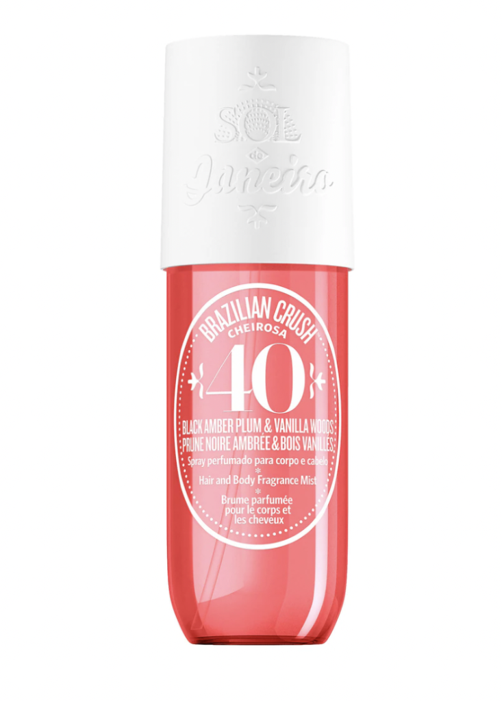 A bottle of Sol de Janeiro's Brazilian Crush Cheirosa '40 fragrance mist, featuring a pink liquid in a clear bottle with a white cap. The label highlights the notes of black amber plum and vanilla woods.